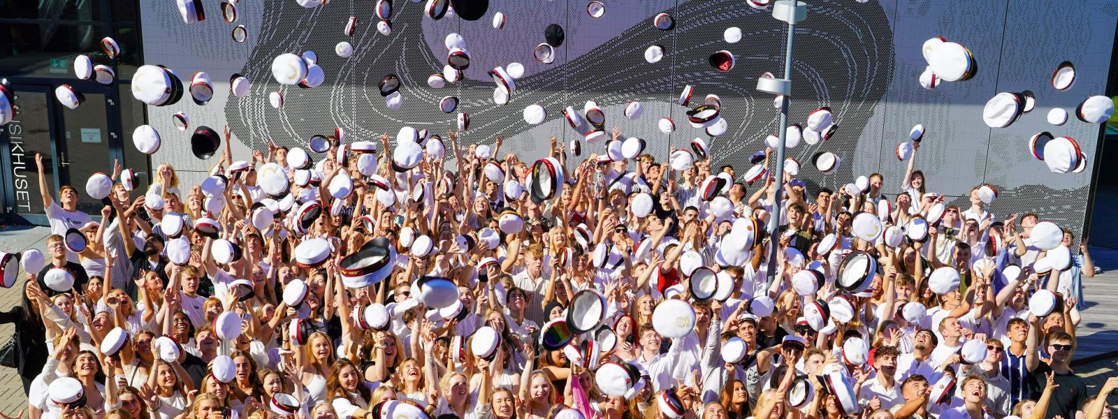 Alle årets studenter kaster deres hue op i luften udenfor Musikhuset.